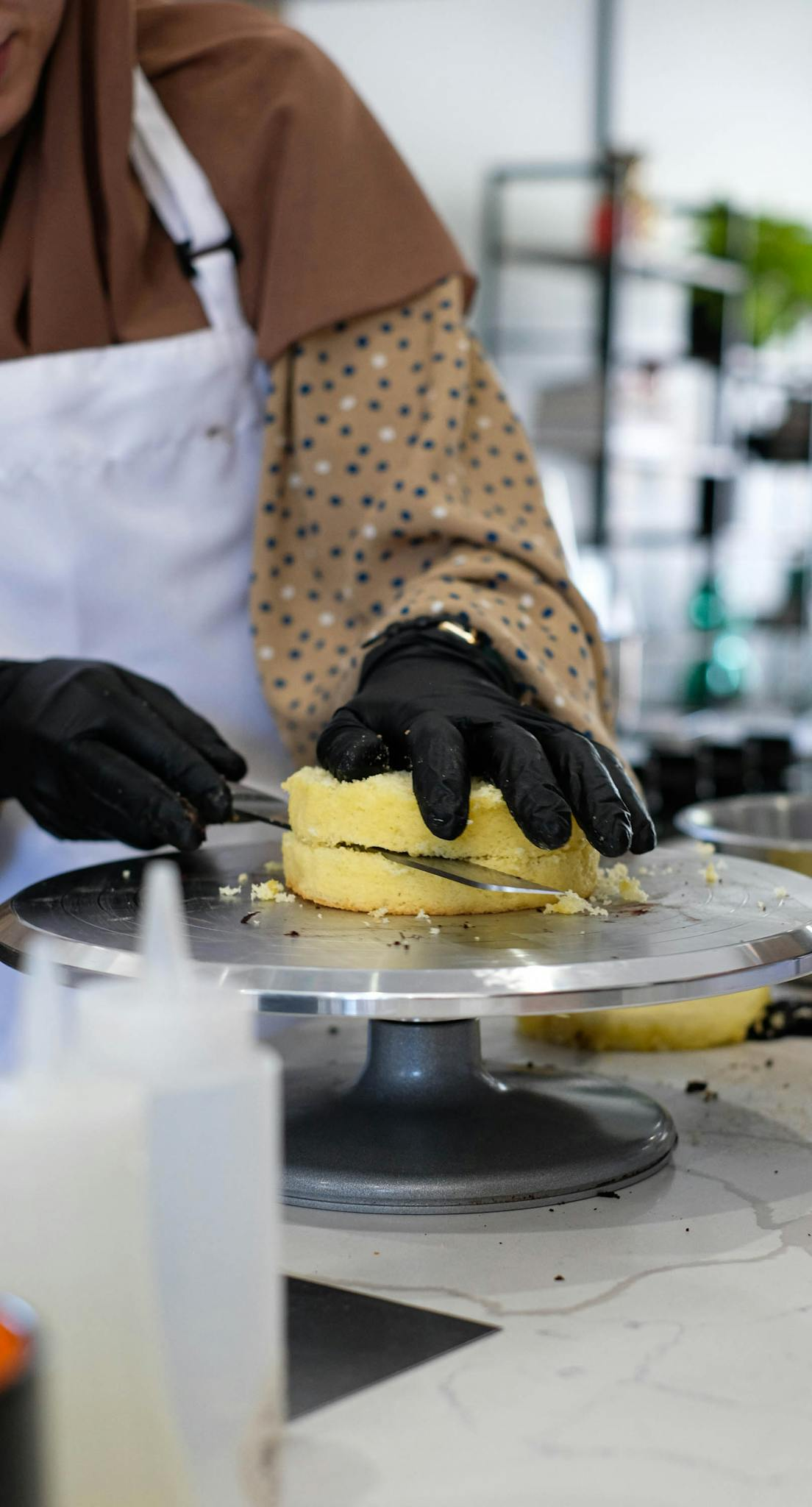 A baker carefully decorates a cake in a modern kitchen setting.